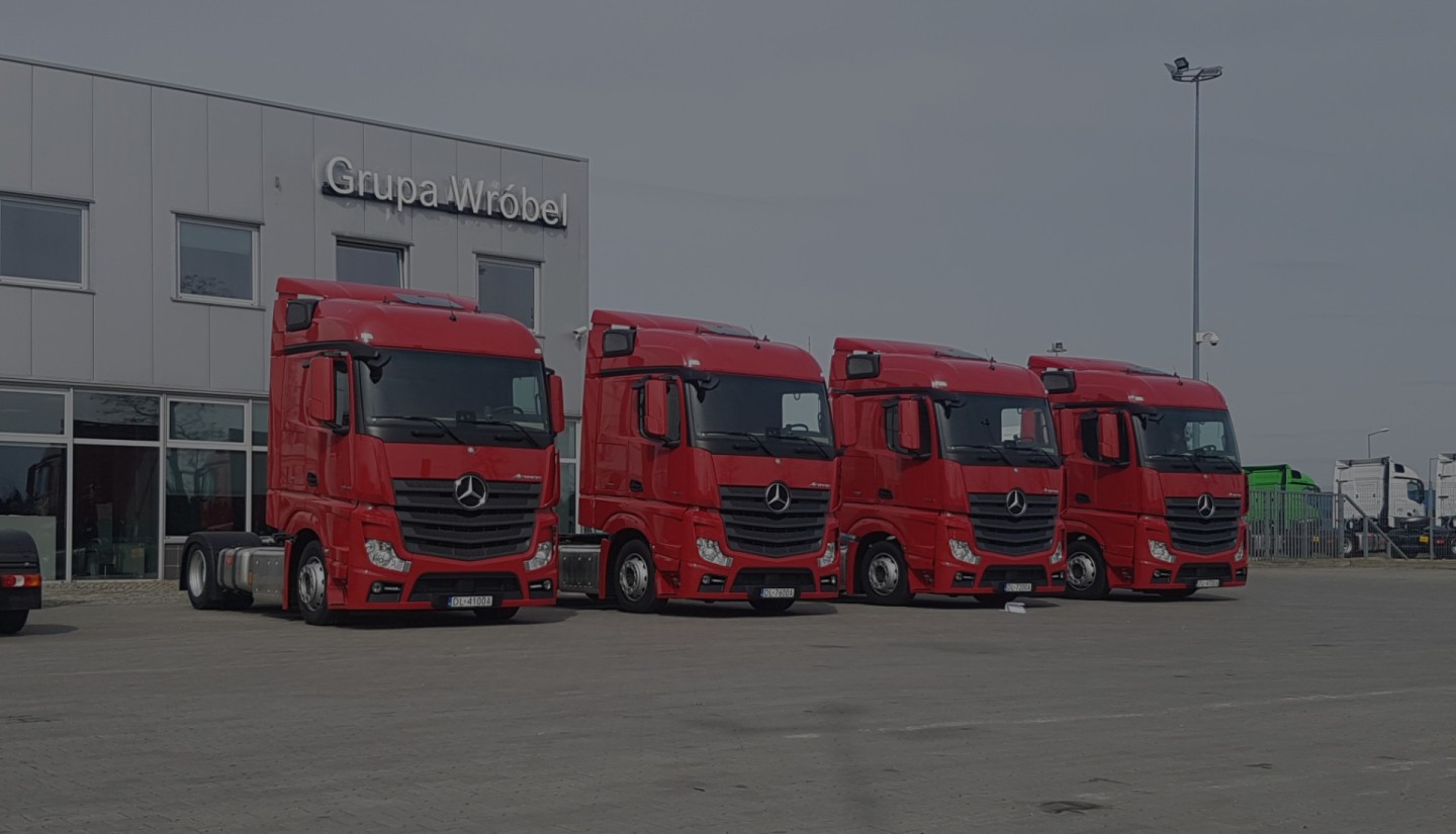 cztery czerwone ciężarówki stoją obok siebie na placu